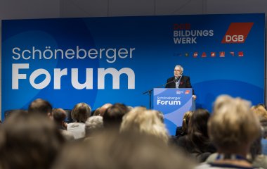Eine Frau steht am Rednerpult vor eine Leinwand mit dem Schriftzug Schöneberger Forum sowie mit Logos des DGB Bildungswerk, des DGB und weiteren Einzelgewerkschaften. Im Vordergrund Menschen in Stuhlreihen von hinten.